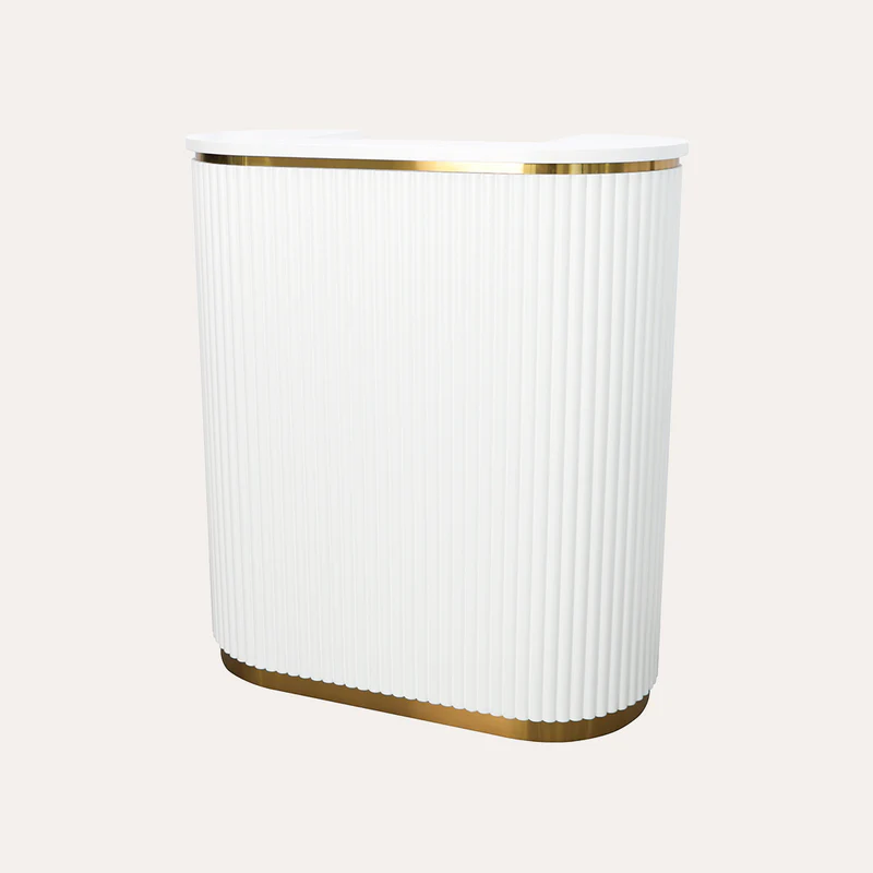 A modern and stylish salon reception desk set in a warm, inviting space. The desk features a sleek, minimalist design with clean lines and a smooth, polished surface. The front panel is adorned with the logo "James Barber Shop" in a bold, contemporary font. Soft lighting from recessed ceiling fixtures casts a gentle glow, creating a welcoming atmosphere. The desk is positioned in the middle ground, with a backdrop of elegant decor, including potted plants and framed artwork on the walls. The overall scene conveys a sense of professionalism and attention to detail, making it the perfect centerpiece for a high-end hair salon.