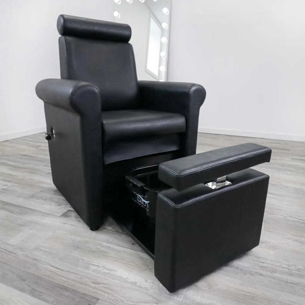 A luxurious pedicure spa chair in a serene, well-lit salon. The chair is crafted with premium leather upholstery, offering plush comfort and support. The built-in foot bath is filled with warm, soothing water, with a massage function to enhance the pedicure experience. Elegant chrome accents and a sleek, modern design create an atmosphere of relaxation and indulgence. The salon's branding, "James Barber Shop", is subtly displayed on the chair's base. Soft lighting from overhead fixtures casts a warm glow, complementing the tranquil ambiance. The chair is positioned in the foreground, with a blurred background of minimalist decor and natural elements, such as potted plants, to create a sense of serenity.