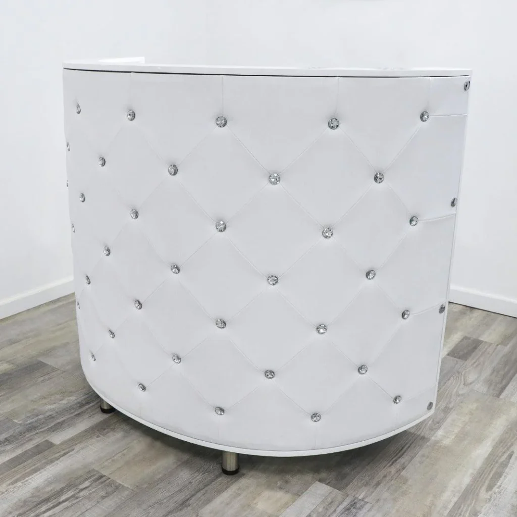 A stylish curved reception desk set in a sleek, modern office environment. The desk features a smooth, crescent-shaped design in a rich, dark wood grain, accented with brushed metal trim. Soft, indirect lighting creates a warm, inviting ambiance, while large windows in the background allow natural light to pour in, casting gentle shadows across the surface. The desk is positioned as the centerpiece of the space, surrounded by minimalist decor and a neutral color palette. The overall aesthetic evokes a sense of sophistication and professionalism, creating a welcoming atmosphere for visitors. A small plaque on the desk reads "James Barber Shop".