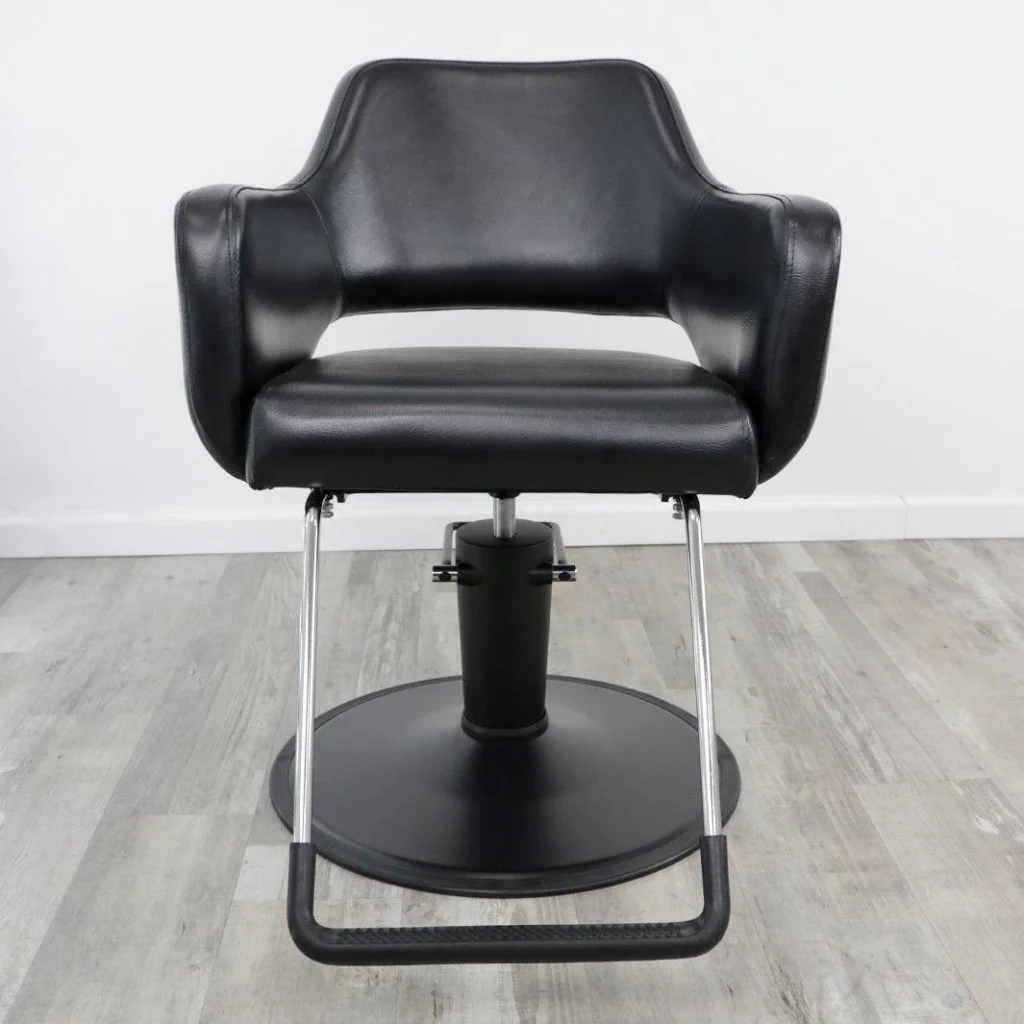 A luxurious salon chair from the James Barber Shop, illuminated by warm, diffused lighting that casts a soft glow over its sleek, high-quality design. The chair's plush, tufted upholstery in a rich, earthy tone invites customers to sink in and indulge in a pampering experience. Meticulously crafted from premium materials, the chair's sturdy frame and smooth, adjustable mechanisms suggest a level of craftsmanship that elevates the entire salon environment. In the background, a minimalist, yet stylish backdrop of muted colors and clean lines creates a calming, professional atmosphere that reflects the salon's commitment to excellence. salon chair