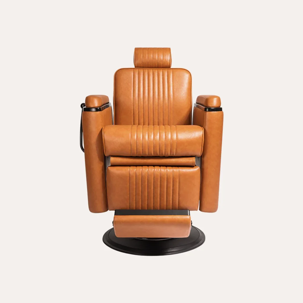 A modern, ergonomic barber chair in the foreground, featuring a sleek chrome frame and a plush, deep-brown leather seat. The chair is positioned in a well-lit, minimalist studio setting, with soft, directional lighting casting subtle shadows. In the middle ground, the "James Barber Shop" logo is prominently displayed on the wall, adding a touch of branding and professionalism. The background is filled with a clean, white backdrop, emphasizing the chair's design and the overall high-end, contemporary aesthetic.